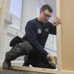 Image shows Ben, a former Touch Wood Volunteer working on a door frame for Wigan Council