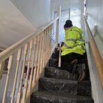 Image shows Ben, a former Touch Wood volunteer working on a domestic stairway handrail in his apprenticeship for Wigan Council